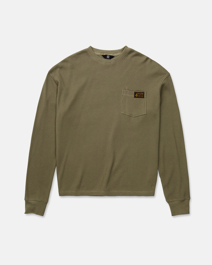The Volcom Men's Overtime Workwear Thermal Long Sleeve Shirt in olive green is crafted from soft cotton knit for a classic thermal appeal. This shirt features ribbed cuffs, a small left chest pocket with a brown rectangular patch label, and is displayed laid flat on a white background.