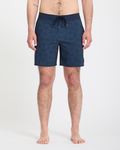 A man stands barefoot against a white background, wearing Volcom Men's Psyche Cotton Stoney 17 navy swim trunks with a drawstring waist. His arms rest at his sides, and only his lower body is fully visible.
