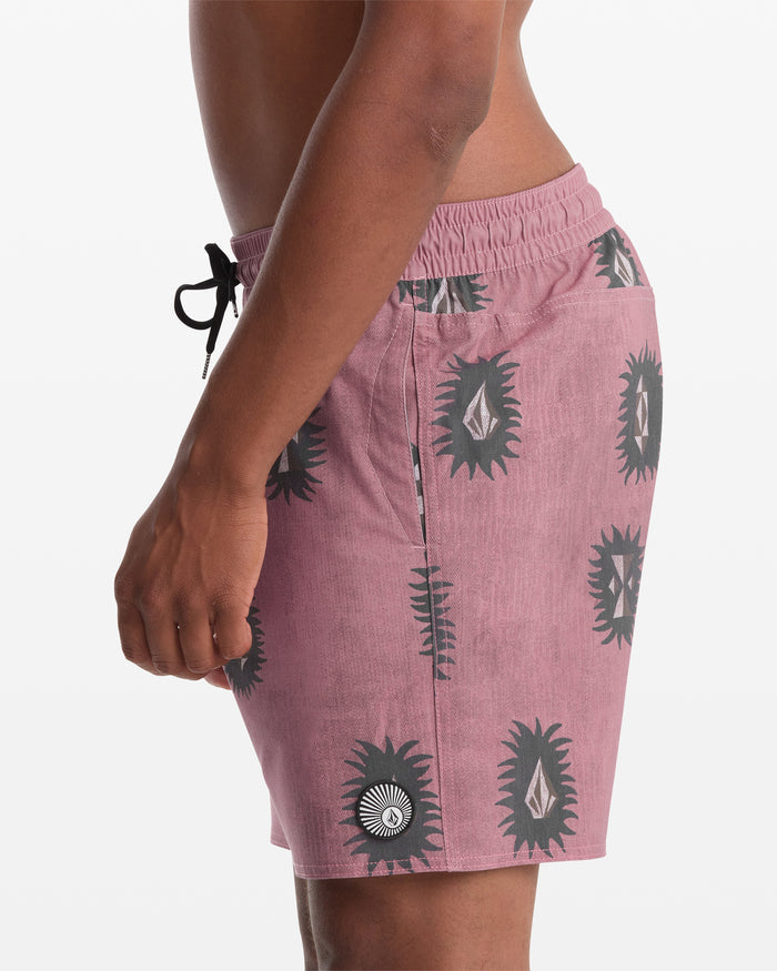 A man stands in profile against a white background, wearing Volcom's Men's Psyche Cotton Trunk 17 shorts in mauve with a black and white abstract sunburst pattern.