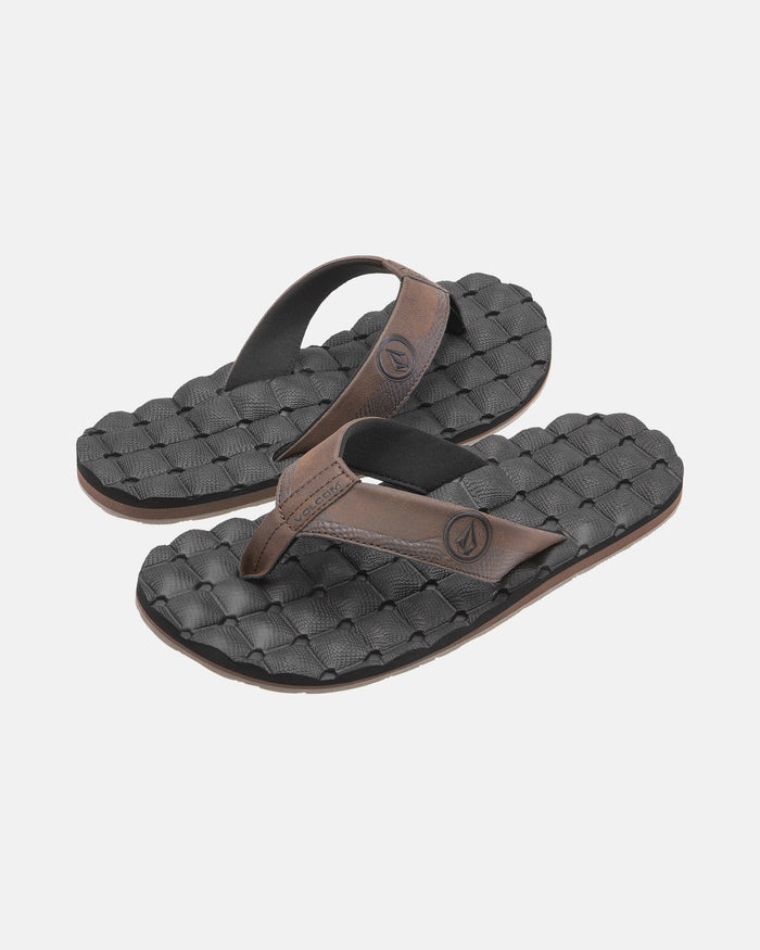 A pair of Volcom Men's Recliner black flip-flop sandals with brown straps and woven textured, extra-grippy soles is displayed on a plain light background.