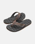 A pair of Volcom Men's Recliner black flip-flop sandals with brown straps and woven textured, extra-grippy soles is displayed on a plain light background.