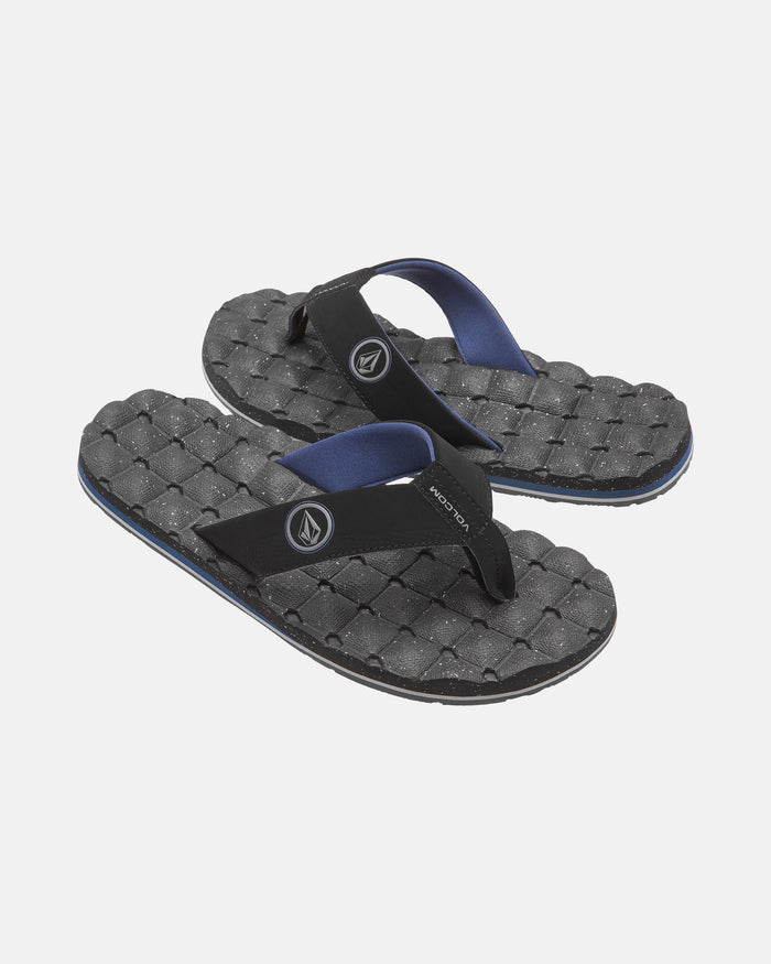 A pair of black Volcom Men's Recliner flip-flops featuring extra-grippy, textured woven-pattern soles and blue-lined straps, shown on a plain white background.
