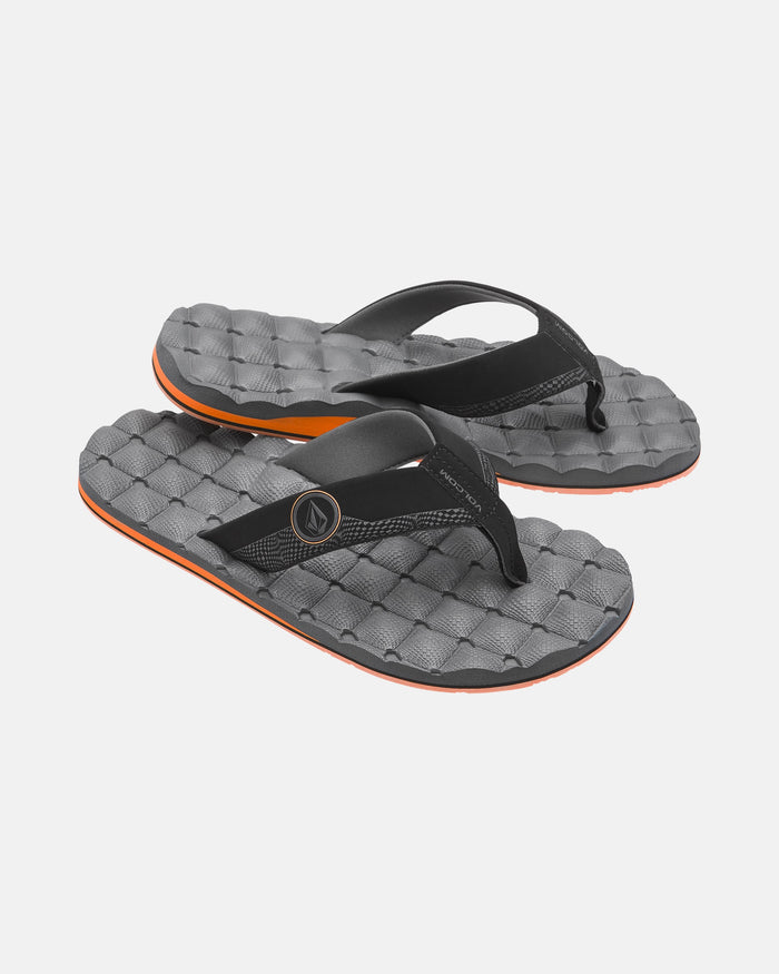 Volcom Men's Recliner sandals feature black straps, textured gray soles with an orange edge, mesh detailing, a circular logo, and cushioned comfort for all-day wear.