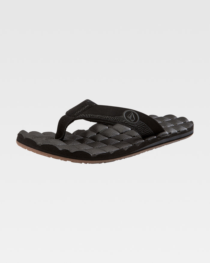 The Volcom Recliner is a black flip-flop with a cushy, textured sole and a fabric thong strap featuring a circular logo, shown on a plain white background.