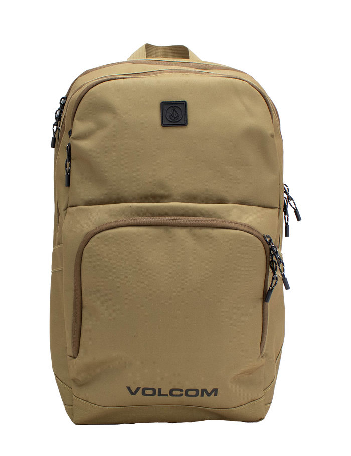 Men's Roamer 3 Backpack by Volcom in tan, featuring multiple zippered compartments, black zippers, and a small black logo patch on the upper front. This spacious 22L backpack includes a padded laptop sleeve for added convenience, with the word VOLCOM printed in black at the bottom front.