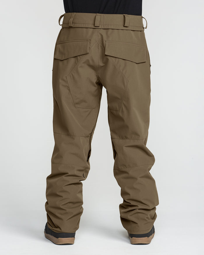 A person wearing the Volcom Men’s Roan 20K Pants in olive-green, paired with black shoes, is shown from the back. Made from recycled fabric, these pants feature back flap pockets and reinforced stitching on the legs. The background is plain white.