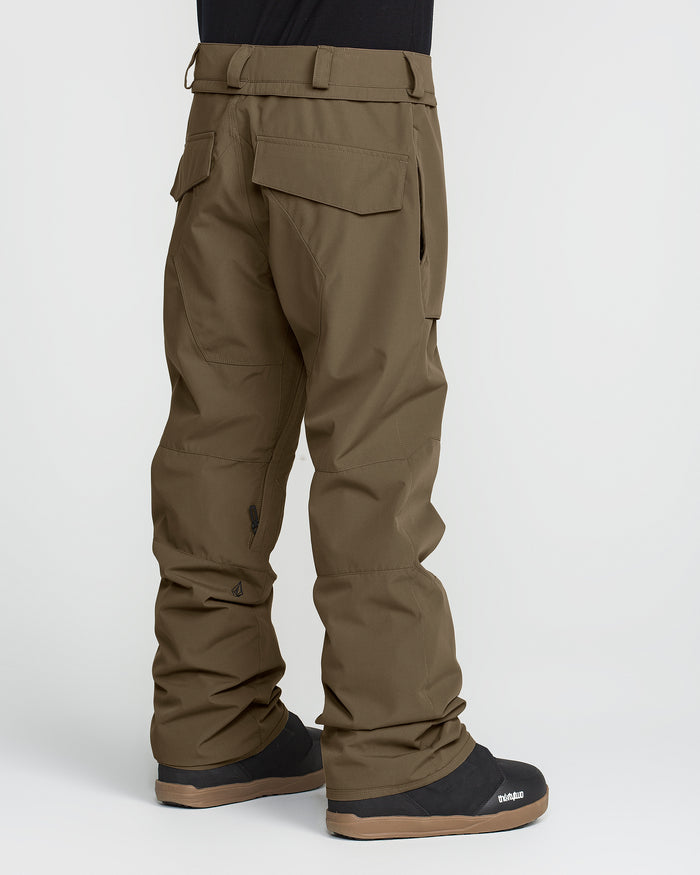 A person wearing Volcom Men’s Roan 20K Pants in olive green, made from recycled fabric, and black boots, shown from the back on a white background.