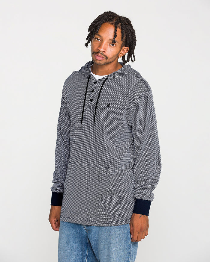 A person with short dreadlocks wears the Volcom Men's Rowan Thermal Long Sleeve Shirt in gray, featuring a front pocket, paired with blue jeans. Standing against a plain white background and looking at the camera, he showcases the midweight warmth and casual style this thermal pullover provides for any occasion.
