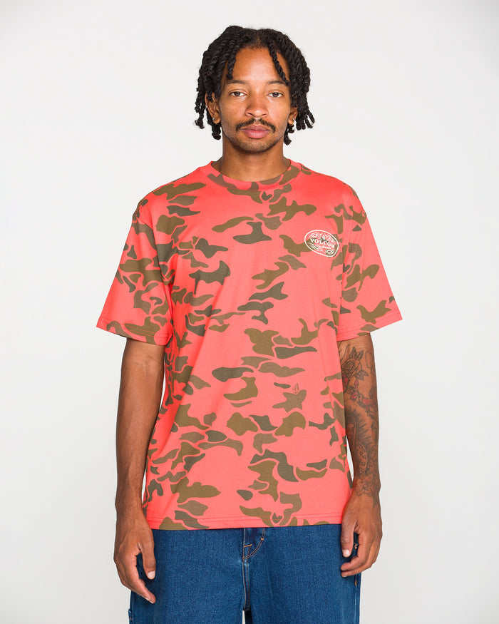 A person stands against a plain white background, facing the camera with hands by their sides, wearing the Volcom Men's Safety Workwear Short Sleeve Tee in red and brown camo made from premium cotton. The T-shirt features a chest logo and is perfect for those seeking both style and comfort in their safety workwear.