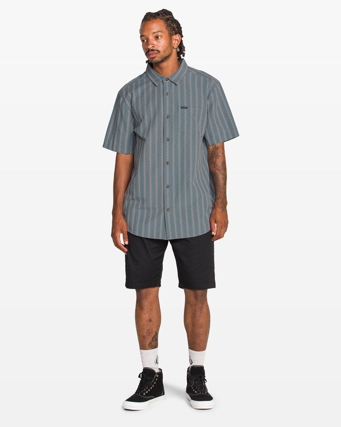 Man wearing a striped shirt and black shorts on a white background
