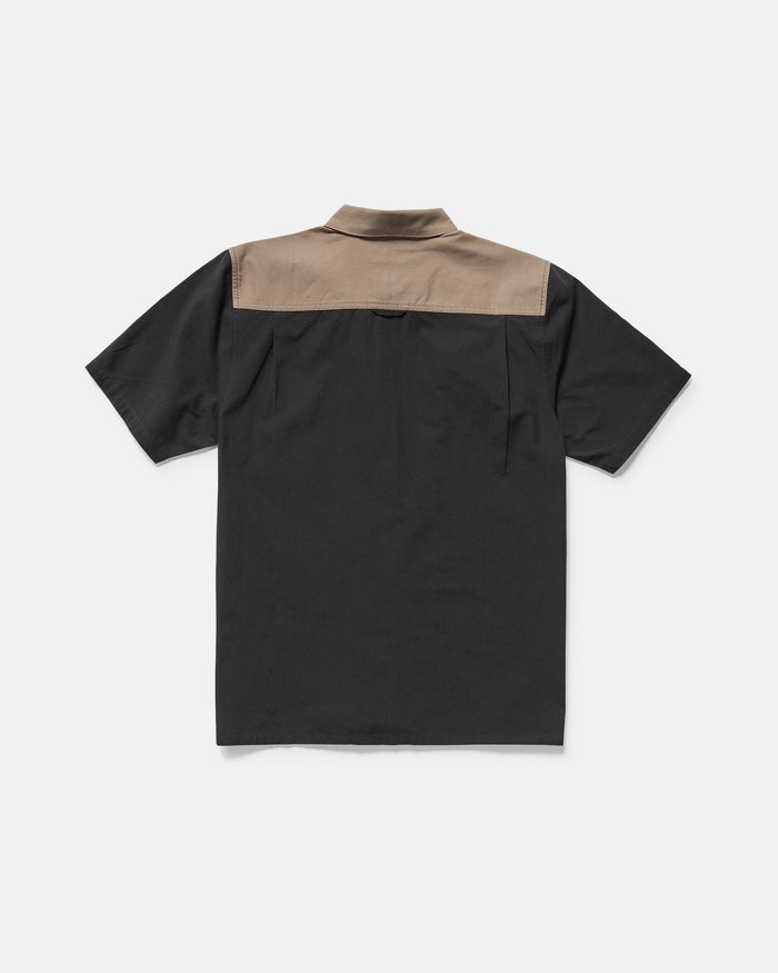 Back view of the Volcom Men's Slab City Short Sleeve Tee featuring a black body, contrasting light brown yoke across the shoulders, and double chest pockets, displayed against a plain white background.