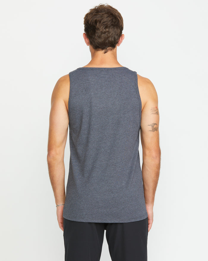 A man with short brown hair is seen from the back, wearing the Volcom Men's Solid Heather Tank and black pants. The plain white background highlights his modern style and the tattoo on his left upper arm.