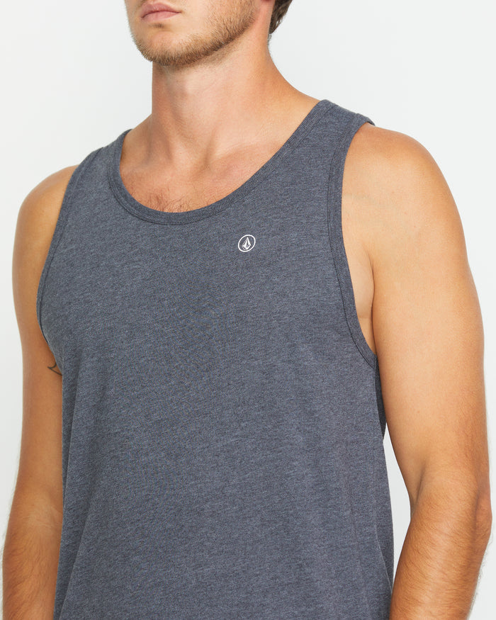 A person models the Volcom Men's Solid Heather Tank, a sleek, modern fitted tank in dark gray with a small white chest logo, against a plain white background. Their face is partially out of frame.