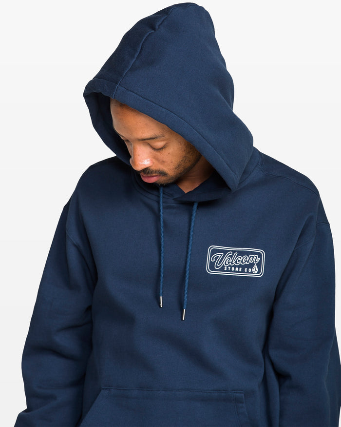Person wearing a navy blue hoodie with a logo on the chest against a white background