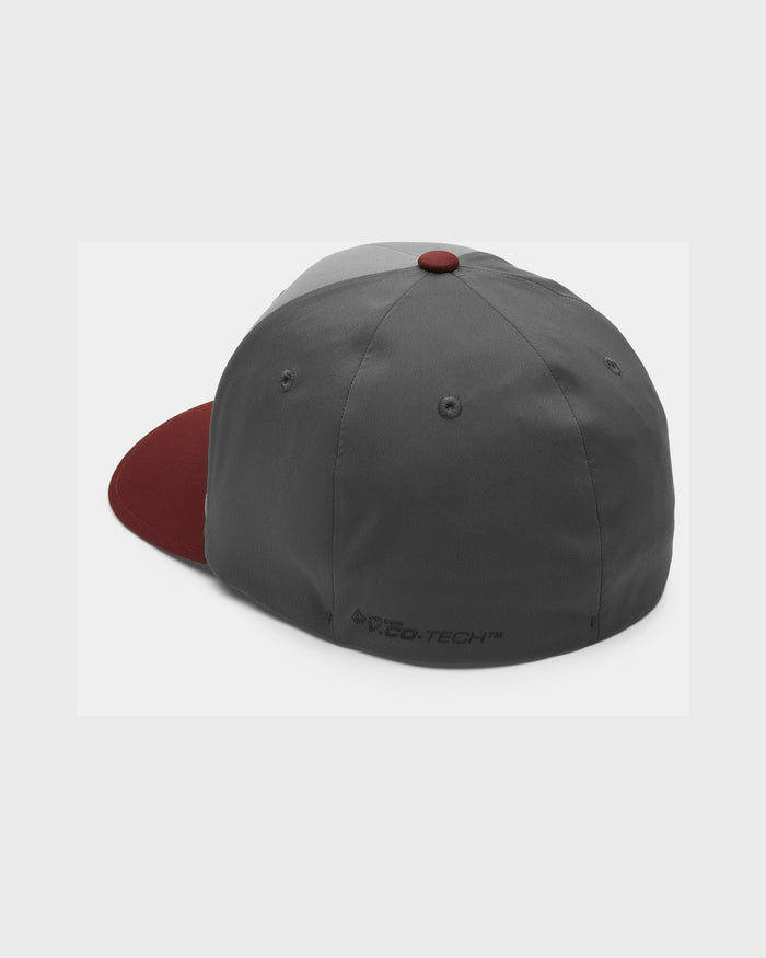 A Volcom Men's Stone Tech Flexfit Delta Hat in gray with a maroon brim and top button, displayed from the back. This athletic fit cap features ventilation eyelets and a small "O-Tech" logo near the bottom edge.