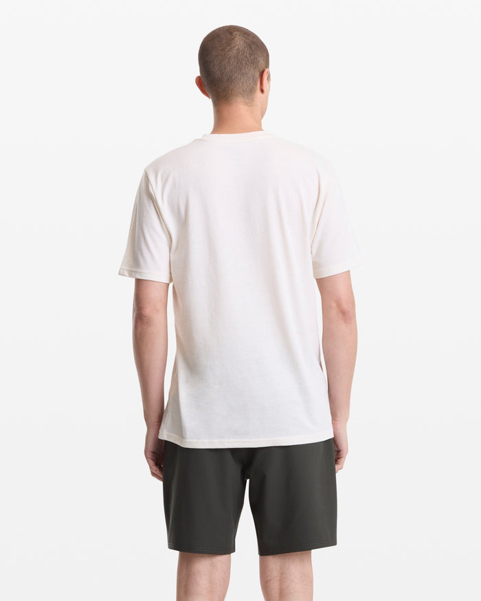 A person faces away from the camera in a Volcom Men's Stoned In Paradise Short Sleeve Tee and dark shorts, set against a white background.