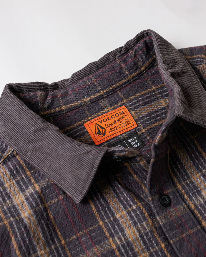 Close-up of Volcom’s Men's Stonevise Plaid Long Sleeve shirt with a corduroy collar and an orange Volcom label inside. The plaid pattern combines brown, yellow, and red shades.
