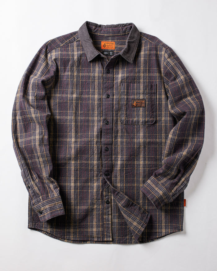 The Volcom Men's Stonevise Plaid Long Sleeve is a workwear-style flannel shirt with purple, gray, and beige plaid, chest pocket, small orange label, and button-up front. Displayed flat on a white background.