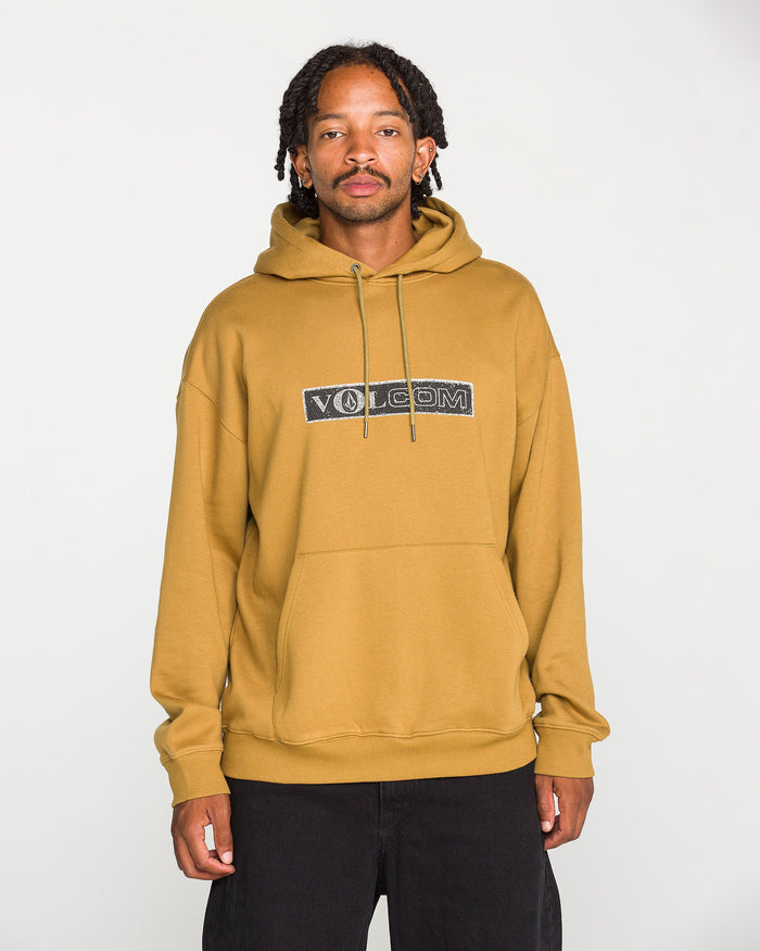 A person wearing the Volcom Men's Super Stoned Pullover in mustard yellow, crafted from brushed-back fleece, paired with black pants, stands against a plain white background and looks at the camera.