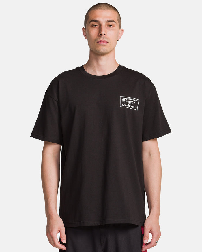A man with short hair wears the Volcom Men's Surf Vitals Modstone Short Sleeve Tee, a loose fit made from premium ringspun cotton with a small white Volcom logo on the left chest, standing against a plain white background.