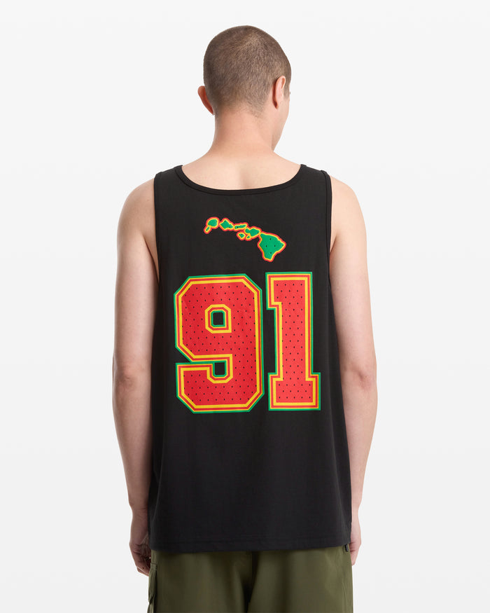 A person wearing the Volcom Men's Swish Tank, featuring a large red and yellow 91 and Hawaiian Islands graphic on the back, stands against a plain white background.