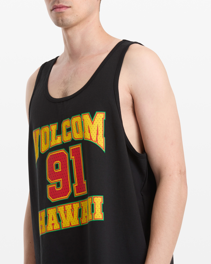 A man wears the Volcom Men's Swish Tank, a black tank top featuring "VOLCOM 91 HAWAII" in bold yellow and red letters. His upper body is shown against a plain white background.