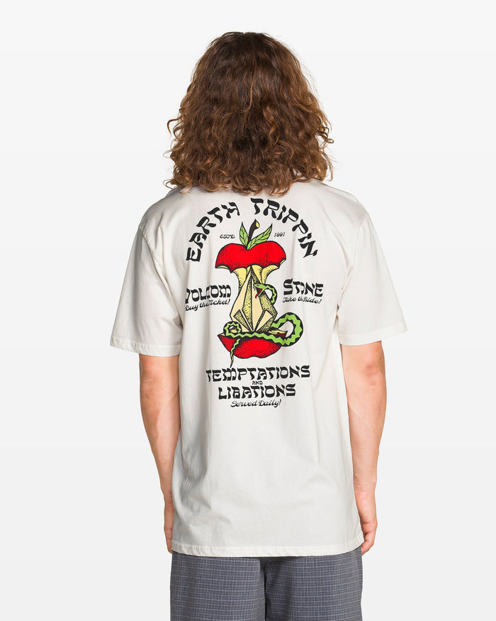 A person with long hair wears the Volcom Men's Temptations Short Sleeve Tee, a soft white cotton crewneck featuring a colorful mushroom and plant graphic on the back, plus the words: EARTH TRIPPIN, BLOOM, SHINE, TEMPTATIONS, LIBATIONS.