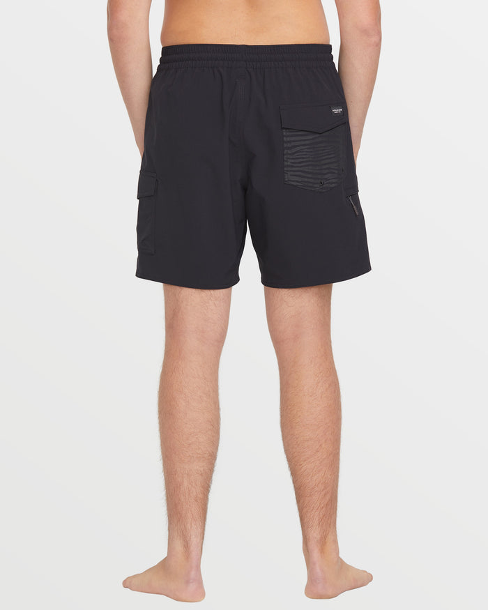 A person stands barefoot facing away, wearing Volcom Men's Truly Liberators black 17-inch trunk shorts with side and back cargo pockets, against a plain white background.