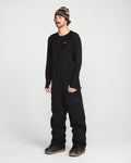 A person wearing a black beanie, a black long-sleeve shirt, and the Volcom Men’s V.Co Sparta Bib—crafted from recycled fabric with waterproof protection—stands against a plain white background.