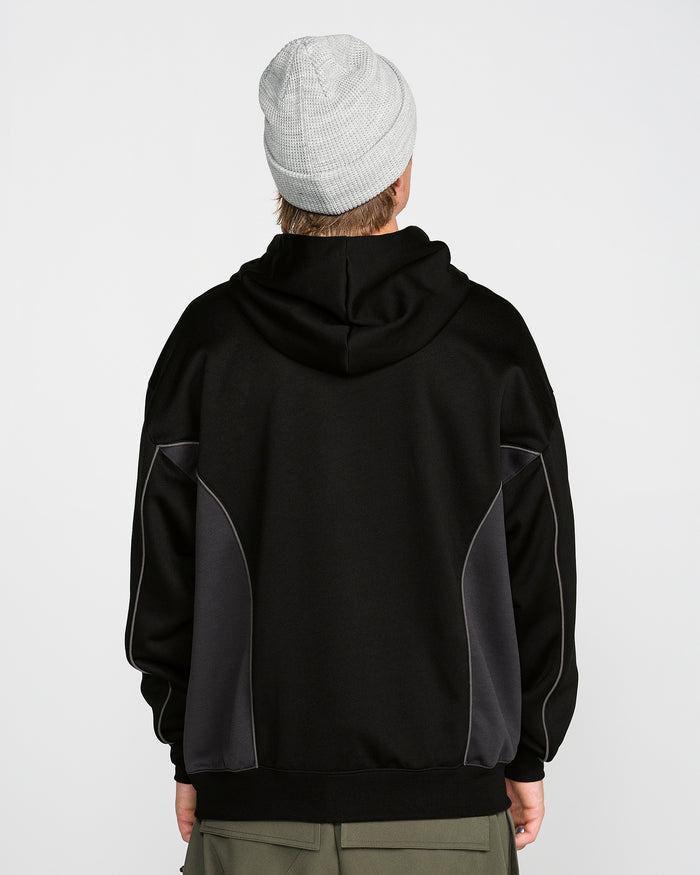 A person is standing with their back to the camera against a plain white background, wearing a light gray knit beanie, olive green pants, and the Volcom Men’s Vital Hydro Pullover Hoodie in black with dark gray side panels.