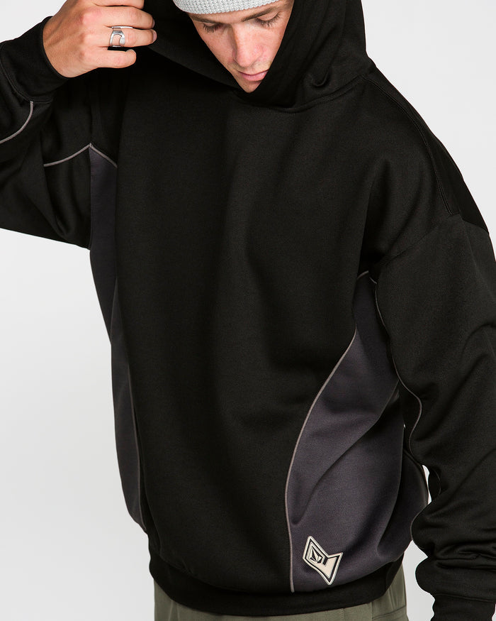 A person wearing the Volcom Men’s Vital Hydro Pullover Hoodie in black and gray, featuring a small geometric logo near the hem, adjusts their hood while looking down.