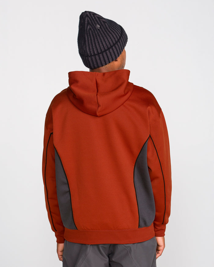 A person is standing with their back to the camera against a plain white background, wearing the Volcom Men’s Vital Hydro Pullover in red with dark gray side panels and a black knitted beanie.