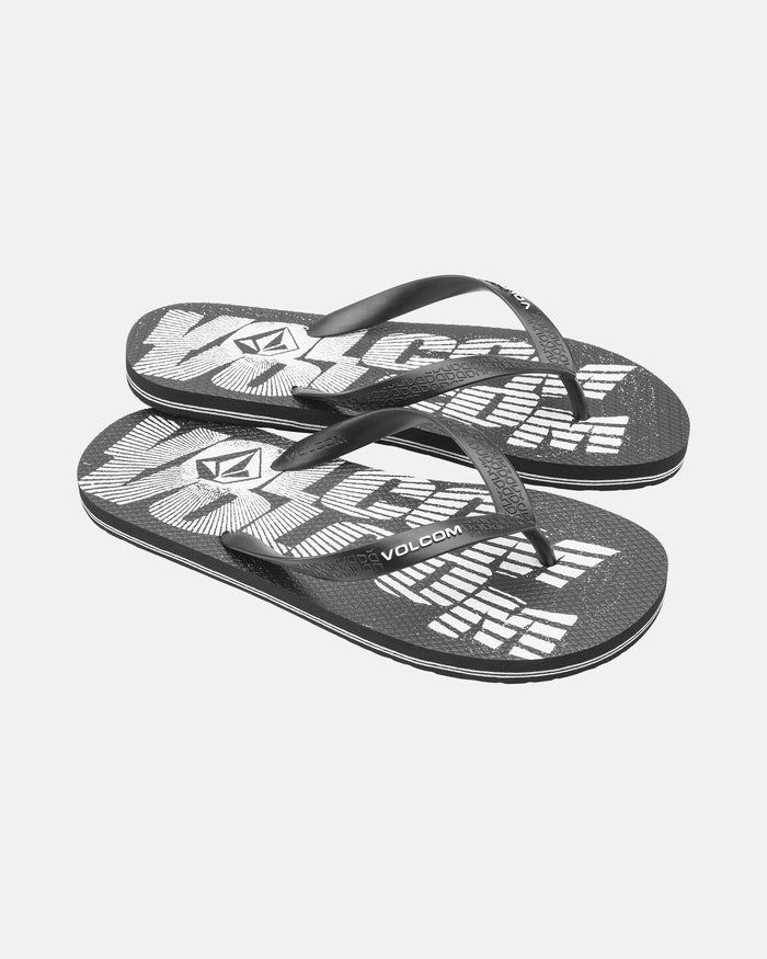 A pair of Volcom Volcomotion Mens flip-flops in black, featuring bold white graphic text and the Volcom logo on the footbeds, displayed on a white background.