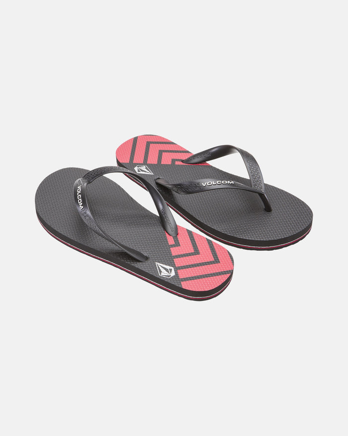 A pair of Volcom Volcomotion Mens black flip-flops with textured soles and diagonal red and black chevron patterns near the toes, displayed on a white background.