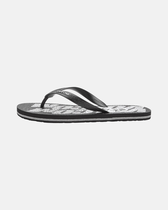 The Volcom Volcomotion Mens sandal is a black flip-flop with a white patterned footbed, black thong strap, and flat sole, shown on a plain white background.