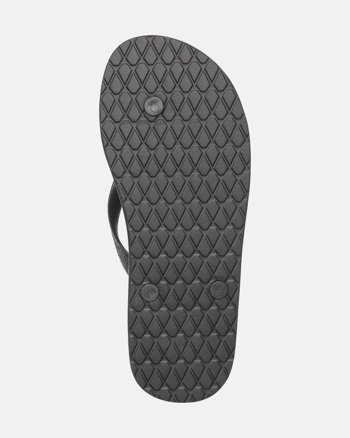 The image shows the bottom sole of a Volcomotion Mens black flip-flop sandal by Volcom, featuring a diamond-patterned tread and three circular plugs.