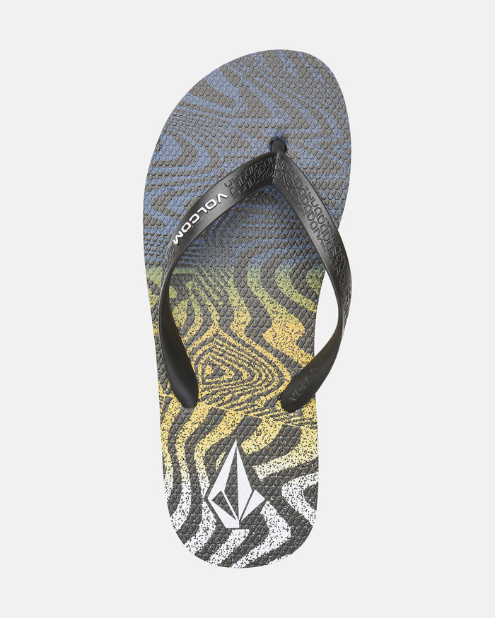 The Volcom Men's Volcomotion flip-flop features a textured sole with a blue, yellow, black, and white abstract pattern and black straps with the VOLCOM logo—combining everyday comfort with signature style.
