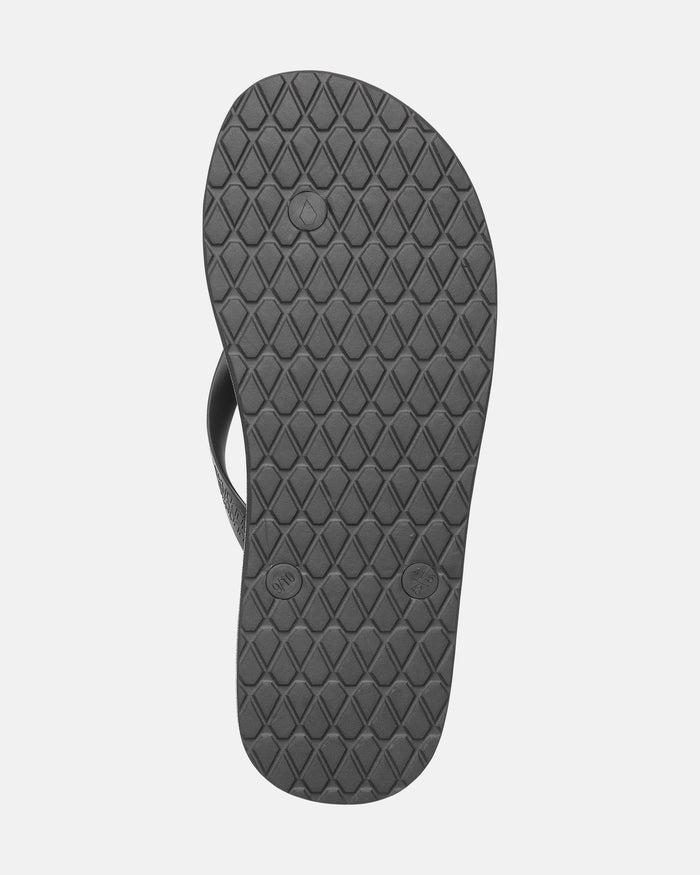 The image displays the bottom view of a single Men's Volcomotion flip-flop by Volcom, featuring a black sole with diamond-patterned tread and circular details, photographed on a white background for everyday comfort in classic Volcom style.