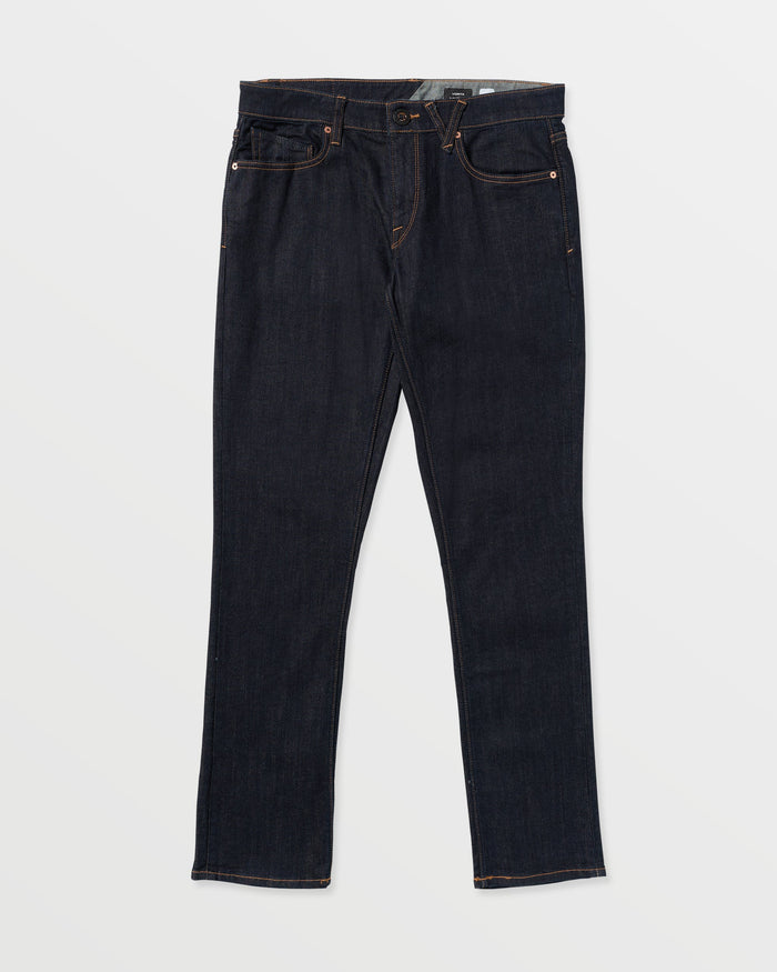 A pair of Volcom Men's Vorta Denim jeans in dark blue slim fit with a straight-leg cut, five pockets, copper stitching, and Water Aware eco-friendly construction is laid flat on a white background.