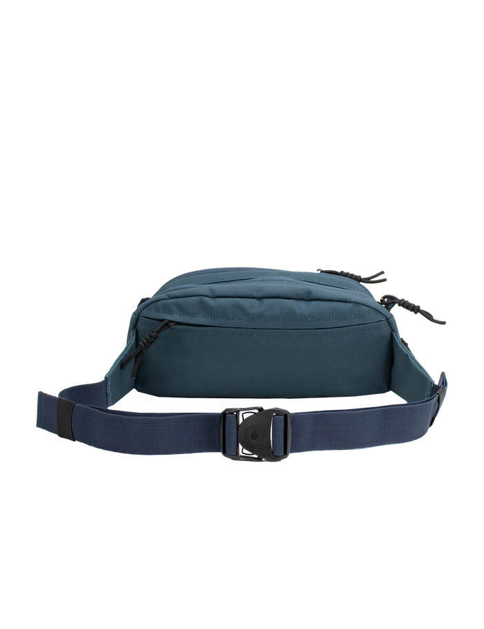 The Volcom Men's Waisted Pack, shown against a white background, features a stylish teal and navy blue design with two zippered compartments and an adjustable strap, making it perfect for hands-free convenience during outdoor adventures.