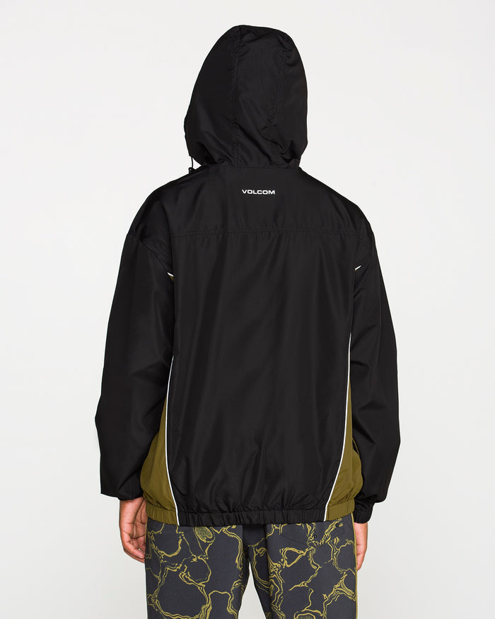 A man is shown from the back against a plain white background, wearing the Volcom Men's Wavestone Jacket in black with olive side panels and patterned pants. The jacket includes a mesh-lined hood for enhanced breathability.