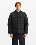 A person wearing a mustard beanie, dark jeans, and the Volcom Men's Westmead Quilted Jacket with buttoned chest pockets stands facing forward against a plain white background.