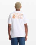 A man with short, curly blond hair wears a white Volcom Men's Workwear Short Sleeve Tee with an orange logo and text on the back, paired with blue shorts, standing against a plain white background.