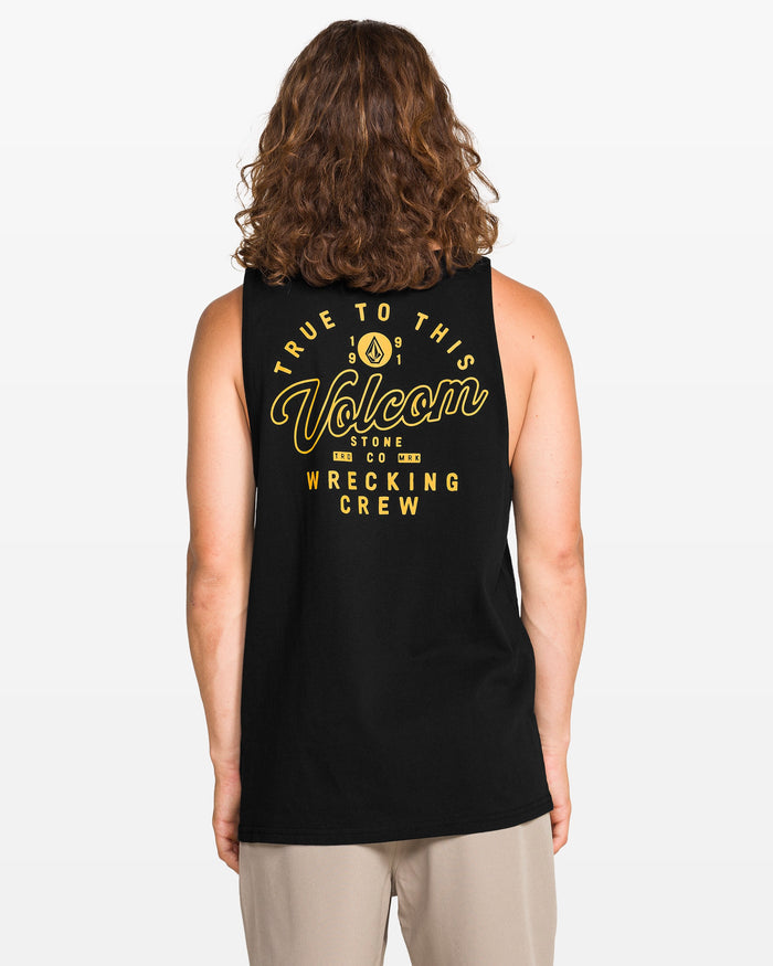 A person with long curly hair faces away from the camera, wearing a classic fit black Volcom Men's Wrecking Tank made of 100% cotton, featuring yellow "True To This Volcom Stone Co Wrecking Crew" text on the back.