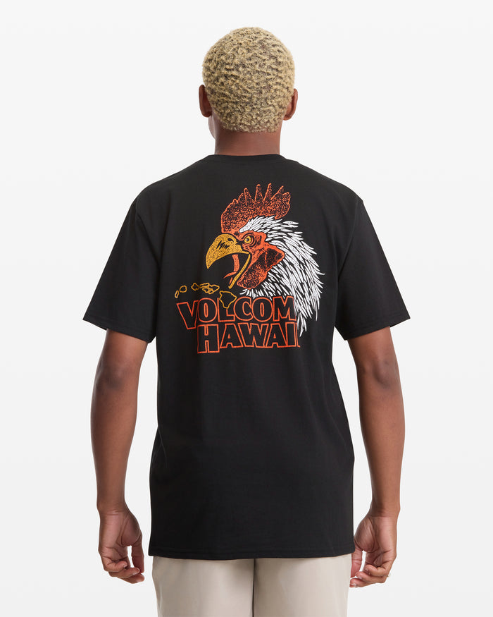 A person with short blond hair is seen from behind wearing the Volcom Men's Yewster Rooster Short Sleeve Tee, a black T-shirt with a colorful rooster graphic and "VOLCOM HAWAII" text on the back.