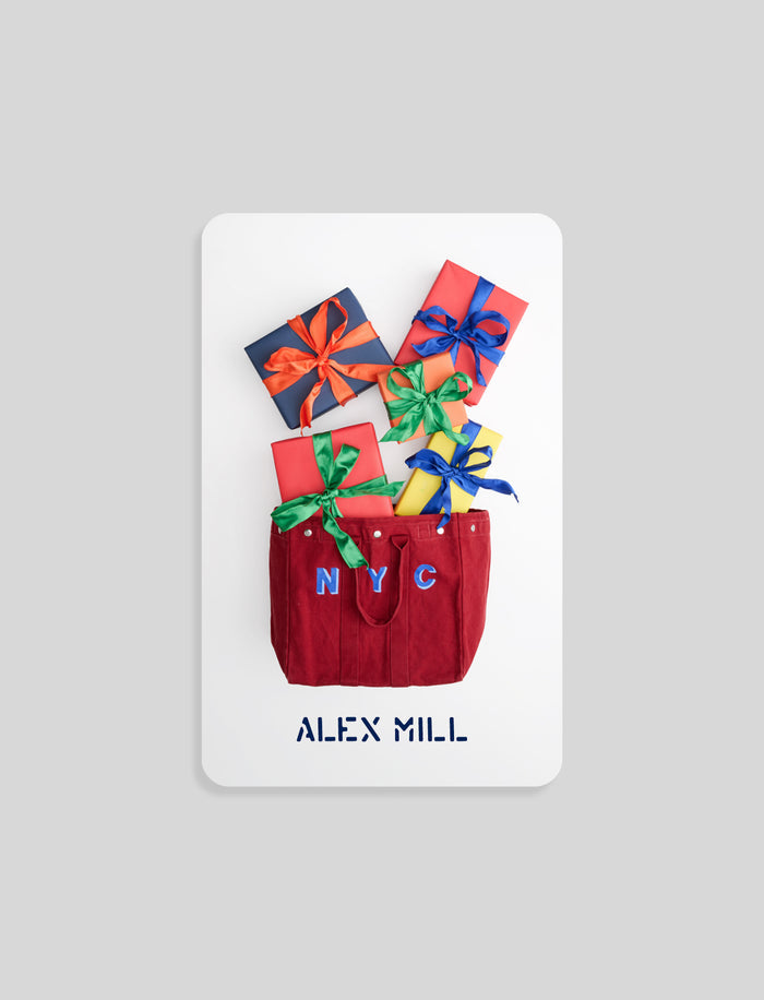 A red monogram tote with NYC letters holds colorful presents, with “ALEX MILL” displayed below—perfect for gifting the Monogrammed Tote IOU Physical Gift Card.