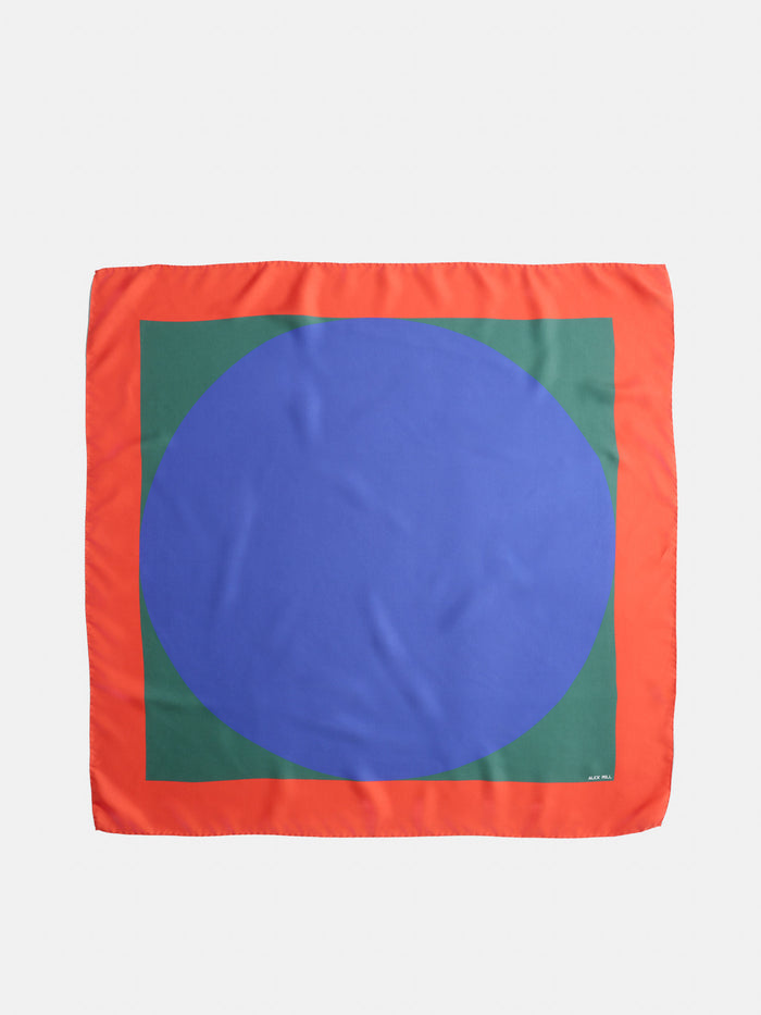 The Pop Art Silk Scarf features a square design with a red border, a green inner square, and a large blue oval centered on the fabric.
