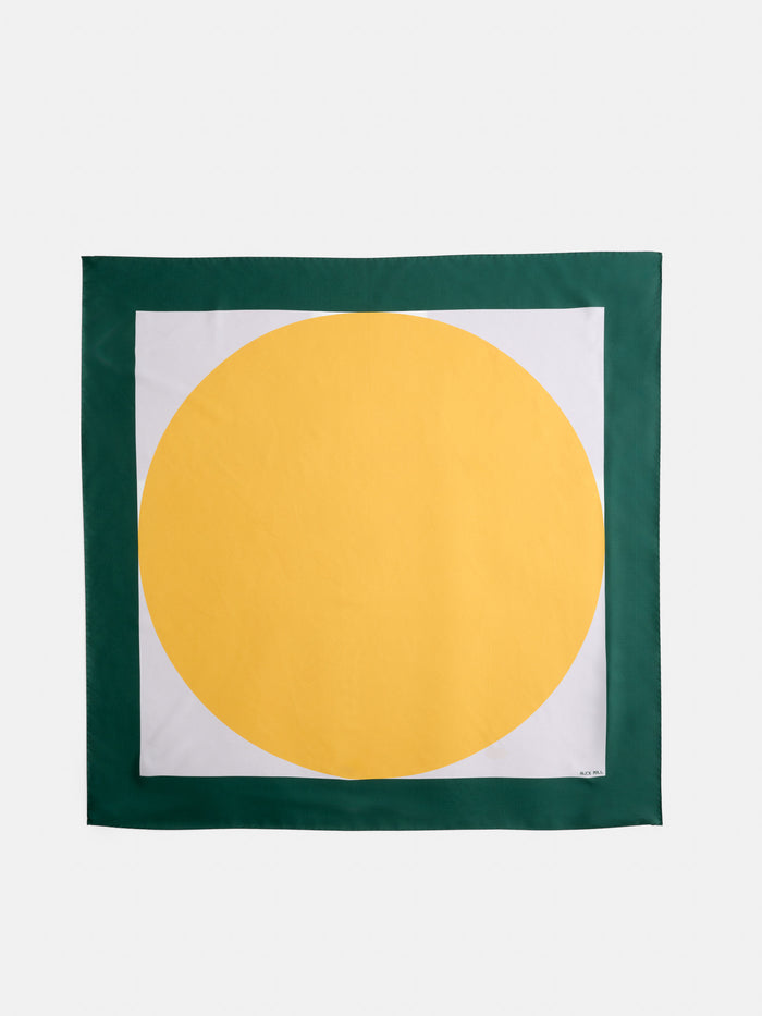 The Pop Art Silk Scarf features a square design with a green border, a white center, and a bold yellow circle dominating the inner area.
