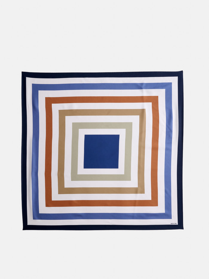 Pop Art Silk Scarf featuring concentric squares in blue, beige, white, and rust on a white background, finished with a dark blue border.
