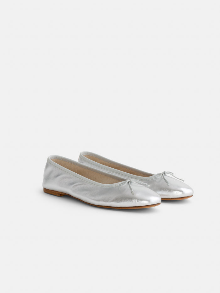 A pair of Prince Street Ballet Flats in silver with small bows on rounded toes, handcrafted in Florence and shown on a plain white background.